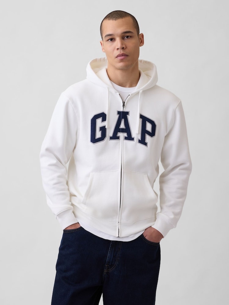 The same white full-zip hoodie with navy arched twill lettering across the chest