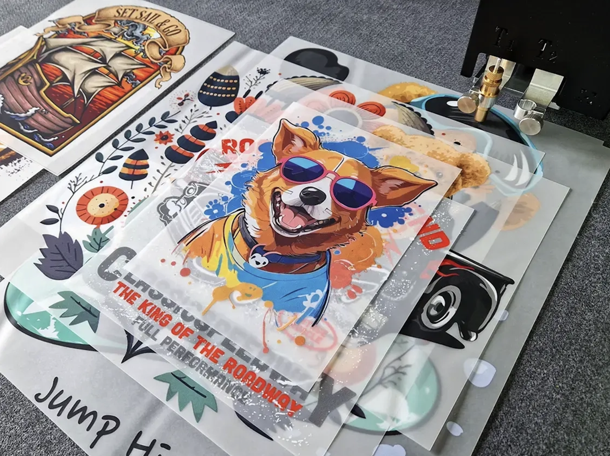 Printed DTF transfer films laid out beside the printer