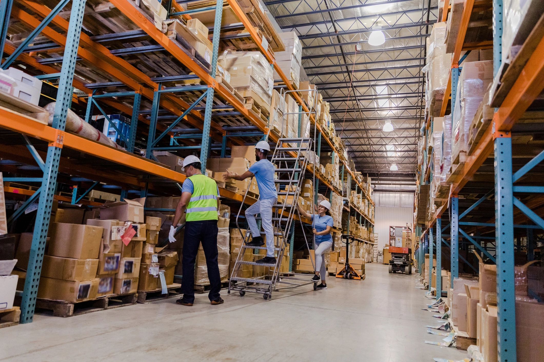 Warehouse employee retrieving a box with coworkers waiting
